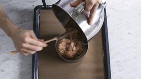 A baker pouring the cake batter into a cake ring