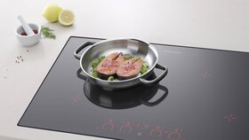 Two delicious salmon steaks frying on an induction hob