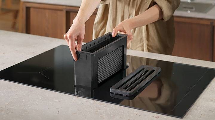 Hands putting back the grease filter on an Extractor Hob